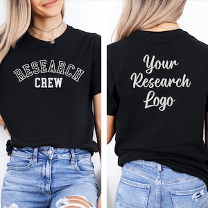 May include: Black t-shirt with white text. The front of the shirt reads "RESEARCH CREW" in a collegiate font. The back of the shirt says "Your Research Logo" in a script font. The model is wearing blue jeans.