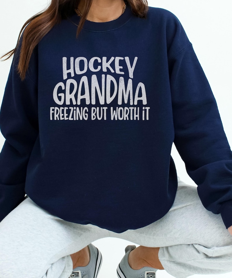 May include: A navy blue sweatshirt with the text "Hockey Grandma Freezing But Worth It" in white lettering.