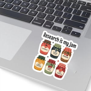 May include: A sticker featuring six jam jars with labels like "Enrollment" and "Protocols." The text "Research is my jam" arches above the jars. The sticker is placed on a laptop.