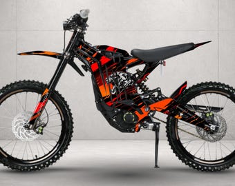 May include: An electric dirt bike featuring a black frame with vibrant orange and red graphic decals. The design includes a stylized panther illustration on the side panel, black spoked wheels, a black seat, and a kickstand for stability.