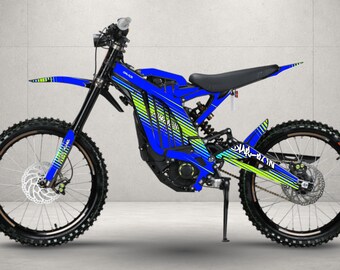 May include: An electric dirt bike featuring a vibrant blue frame with bright green and yellow graphic accents. The bike is equipped with black knobby tires, disc brakes, a black seat, and a kickstand, showcasing a sleek design for off-road use.