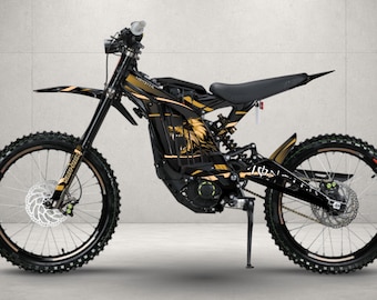 May include: A black electric dirt bike featuring gold graphic accents, including a wolf head design on the frame. The bike is equipped with knobby tires, disc brakes, a front suspension fork, a rear shock absorber, and a kickstand for stability.