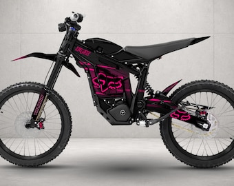 May include: A black electric dirt bike featuring bright pink Fox Racing graphics on the frame and rear fender. The bike has a black seat, black spoked wheels with knobby tires, a front suspension fork, and the word Talaria printed on the front fork.