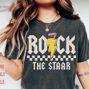 May include: A gray t-shirt with a graphic design of a yellow lightning bolt with pink accents and the text "ROCK THE STAR" in white letters.