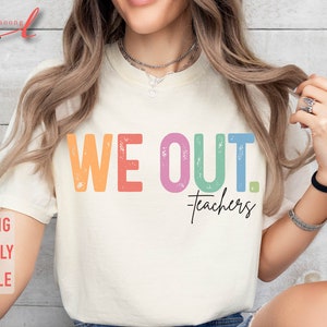 May include: A white t-shirt with the text "WE OUT. Teachers" in rainbow colors. The text has a distressed, vintage look.