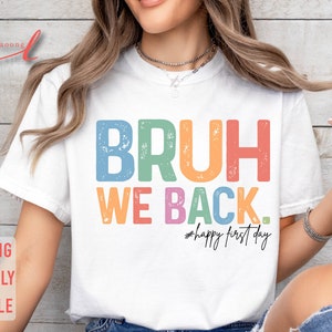 May include: A white t-shirt with the text "BRUH WE BACK. #happy first day" in rainbow colors with a distressed effect.
