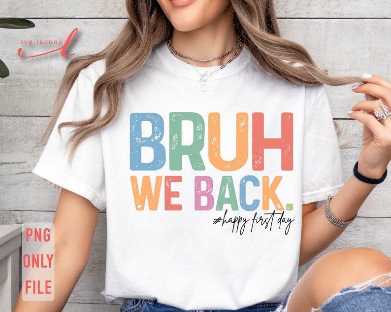 May include: A white t-shirt with the text "BRUH WE BACK. #happy first day" in rainbow colors with a distressed effect.