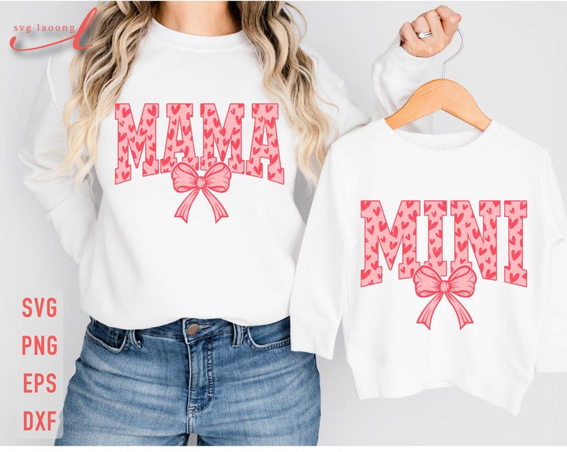 May include: Two white shirts with pink heart print designs. The larger shirt says "MAMA" with a pink bow. The smaller shirt says "MINI" with a pink bow.