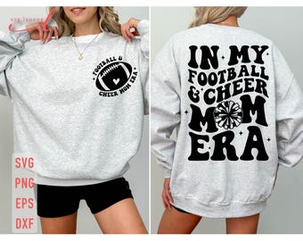 May include: Gray sweatshirt with black text that reads "In My Football & Cheer Mom Era" with a black and white cheerleader pom pom graphic. The sweatshirt is being modeled by a person.
