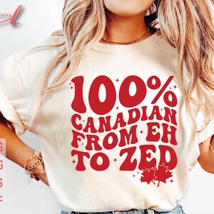 Pu&ograve; includere: Una maglietta bianca con una grafica rossa che dice "100% CANADESE DA EH A ZED" con un design a foglia d'acero rossa.