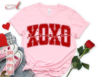 May include: Pink t-shirt with a red "XOXO" graphic featuring a heart and a string of Xs and Os. The graphic has a distressed look.