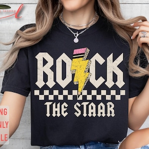 May include: Black t-shirt with a yellow lightning bolt graphic and the text "Rock the Star" in white.