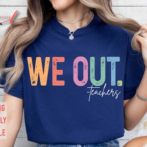 May include: A navy blue t-shirt with the text "WE OUT. teachers" in rainbow colors. The text has a distressed, vintage look.