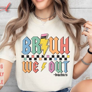 Peut inclure: Un t-shirt blanc avec un graphique color&eacute; qui dit "BRUH WE OUT -teachers". Le graphique est dans un style r&eacute;tro avec un &eacute;clair et un motif &agrave; carreaux.