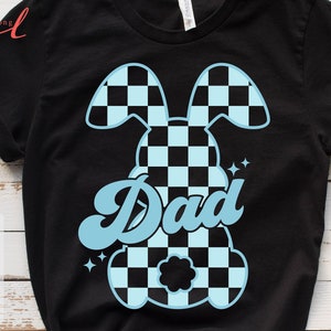 May include: A black t-shirt with a blue checkered bunny design and the word "Dad" in a retro font.