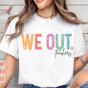 May include: A white t-shirt with the text "WE OUT. -teachers" in rainbow colors. The text has a distressed, vintage look.