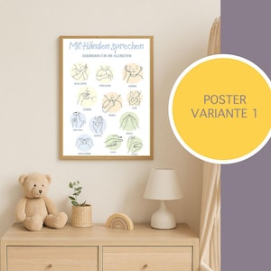 Puede incluir: Un p&oacute;ster enmarcado con el texto "Mit H&auml;nden sprechen" e ilustraciones de gestos con las manos. El p&oacute;ster incluye las palabras "GEBARDEN F&Uuml;R DIE KLEINSTEN" y "POSTER VARIANTE 1". El p&oacute;ster se muestra en una c&oacute;moda de madera con un oso de peluche y una l&aacute;mpara.