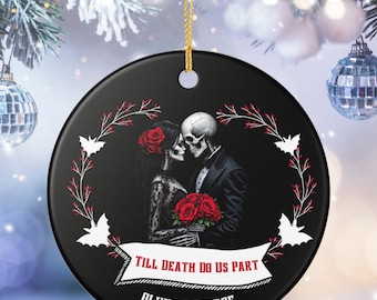 May include: A round black ceramic ornament featuring a skeleton couple in formal attire holding a bouquet of red roses. The design includes a white banner with the text "TILL DEATH DO US PART" and the names "OLIVIA & GEORGE" with the year "2026".