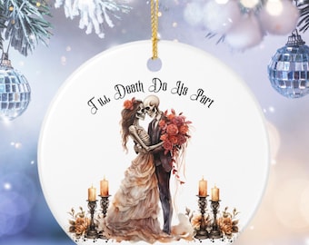 May include: A round white ceramic ornament featuring a skeleton couple embracing, with the text 'Till Death Do Us Part' above them. The design includes red roses, lit candles in holders, and the names 'Olivia & George' with the year '2026' below.