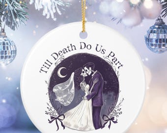 May include: A round white ceramic ornament featuring a black and purple illustration of two skeletons in wedding attire embracing under a crescent moon. The text reads Till Death Do Us Part, Olivia & George, and 2026. It hangs from a gold string.