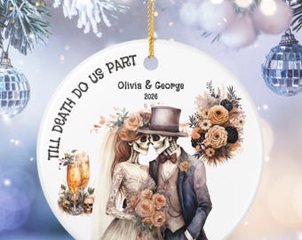 May include: A round white ceramic ornament featuring a skeleton bride and groom illustration with the text Till Death Do Us Part, Olivia & George, and 2026. The design includes a bouquet of flowers, two champagne glasses, and two skulls.