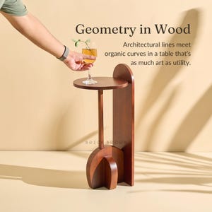May include: A dark brown wooden side table with a circular top and a curved base. The table has a tall, slender stem and a vertical support. The text "Geometry in Wood" is visible.