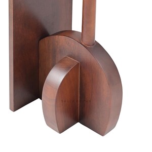May include: Close-up of a wooden object with a dark brown finish. The object has a rectangular base, a curved central section, and a cylindrical element extending upwards. The text "BRICK BROWN" is visible.