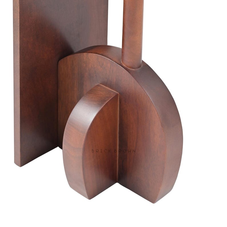 May include: Close-up of a wooden object with a dark brown finish. The object has a rectangular base, a curved central section, and a cylindrical element extending upwards. The text "BRICK BROWN" is visible.