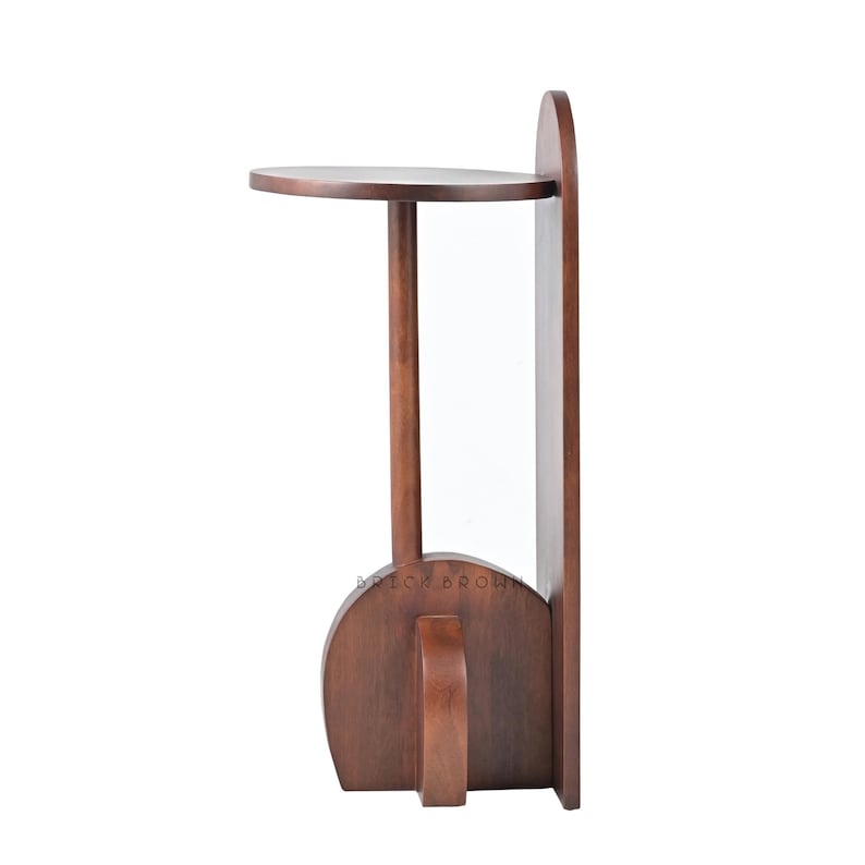May include: A dark brown wooden side table with a round top and a vertical back panel. The table has a single leg supporting the top and a curved base with a handle. The text "BRITON BROWN" is visible on the base.
