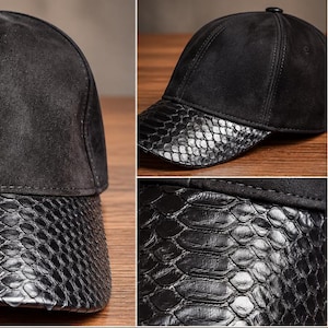 May include: A black baseball cap featuring a matte suede crown and a glossy, textured snakeskin-patterned brim. The back includes an adjustable strap with a metal buckle, and the interior is lined with a black quilted fabric for structure.