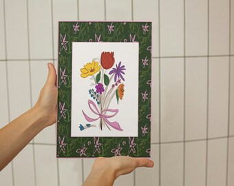 May include: A framed illustration of a bouquet of flowers with a pink ribbon. The flowers are red, yellow, orange, purple, and blue. The frame has a green background with a pink floral pattern.