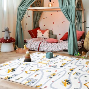 May include: A child's bedroom with a white rug featuring a road and construction vehicle design. The room includes a wooden bed frame with green curtains, a mushroom-shaped stool, and decorative pillows. The bedding has a floral pattern.