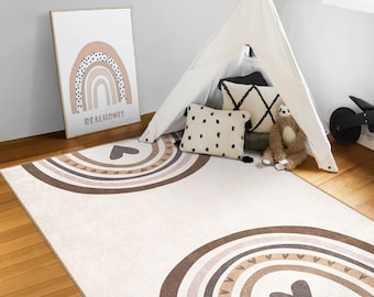 May include: A beige and brown area rug with a rainbow and heart design. The rug has a white background with brown and beige stripes forming a rainbow shape. The center of the rug has a large brown heart.
