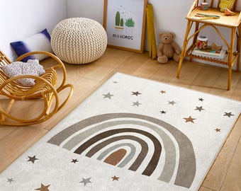 May include: A white and brown rainbow rug with brown stars on a light wood floor. The rug features a multi-colored rainbow with a brown center and a white background. The rug is perfect for a child's room or play area.