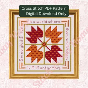 May include: A framed cross-stitch pattern featuring four stylized autumn leaves in shades of red and orange. The text reads "in a world where there are Octobers" and "I'm so glad I live" with the author's name, L.M. Montgomery. The frame is gold.