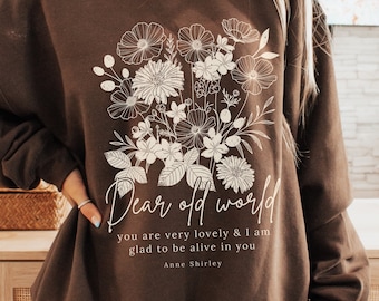 May include: A brown sweatshirt with a white floral design and the text "Dear old world you are very lovely & I am glad to be alive in you Anne Shirley".