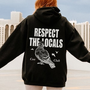 May include: Black hoodie with a white graphic of a pigeon and the text "Respect the Locals" with "Coo Club" underneath.