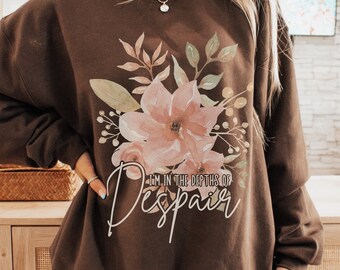 May include: A brown sweatshirt with a floral design and the text "I'm in the depths of Despair" printed on the front.