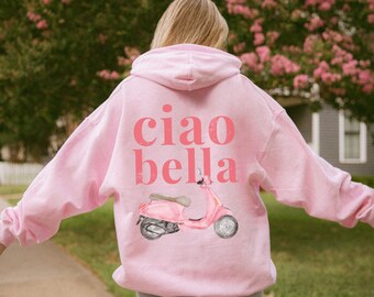Peut inclure: Sweat-shirt rose avec un motif de scooter rose et le texte "ciao bella" au dos.