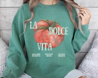 Peut inclure: Sweat-shirt vert avec un graphique de tomate et le texte "La Dolce Vita". Le texte "Locally Grown and Harvested", "Fresh Sicilian Tomatoes", et "Pizza Pasta Bruschetta" est imprimé sous le graphique.