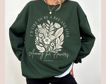 May include: A dark green sweatshirt with a white floral design and the text "I'd like to be a bee and live among the flowers, Anne Shirley".