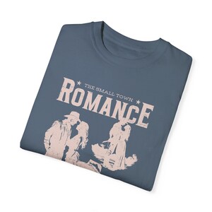 Comfort Colors Shirt in the Color blue jean. Cowboy/Western Romance Book Shirt. Text:The small town romance, love stories of the real west, western love trails;.