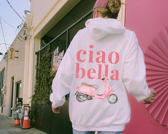 Peut inclure: Sweat-shirt blanc avec un graphique de scooter rose et le texte "ciao bella" imprimé au dos.