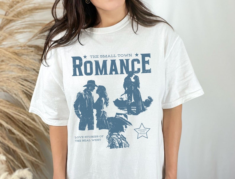 Comfort Colors Shirt in the Color white. Cowboy/Western Romance Book Shirt. Text:The small town romance, love stories of the real west, western love trails;.