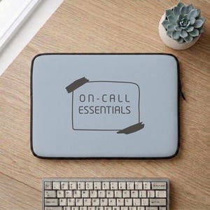 Puede incluir: Una funda rectangular para portátil de color azul claro con un borde negro y un gráfico central de una nota rectangular sujeta por dos trozos de cinta adhesiva. El texto ON-CALL ESSENTIALS está impreso en negro en la parte frontal.