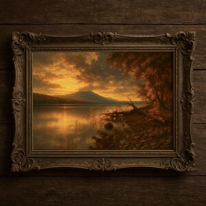 Puede incluir: Pintura de paisaje enmarcada que representa una serena escena lacustre al atardecer. El cielo está encendido con tonos naranja y amarillo, reflejándose en el agua. El marco ornamentado, de color marrón oscuro, complementa los tonos cálidos de la obra.