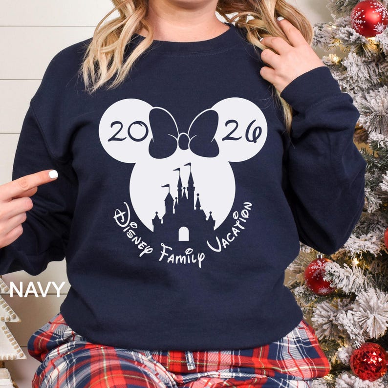 A woman wearing a navy blue sweatshirt with a white graphic design featuring a castle and the text "Disney Family Vacation" printed on it.