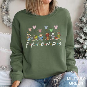 A woman wearing a green sweatshirt with a graphic of Disney characters and the word "FRIENDS" printed on it.