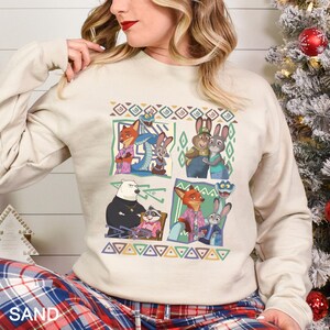 A woman wearing a white sweatshirt with a graphic of cartoon animals, including a fox, rabbit, and bear, arranged in a collage-like manner.