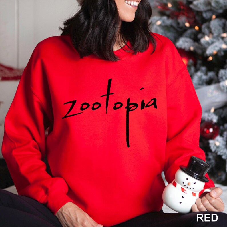 A woman wearing a red sweater with the word "Zootopia" printed on it, holding a snowman toy.